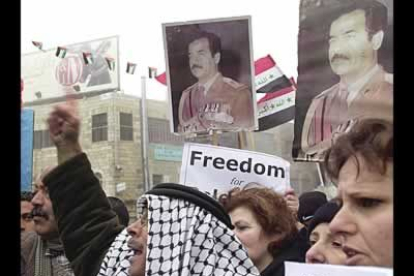 Palestinos portan la bandera iraquí e imágenes de Huseín frente a la embajada británica en la ciudad de Ramallah.