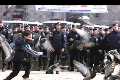 Un niño jugando ante la policía turca que se mantiene en guardia ante una manifestación contra el conflicto bélico en Irak.