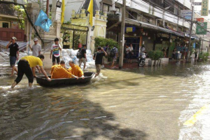 Dos monjes transportados en barca por una calle de Bangkok, la metrópoli por la que avanza la tromba de agua que anega la meseta central de Tailandia.
