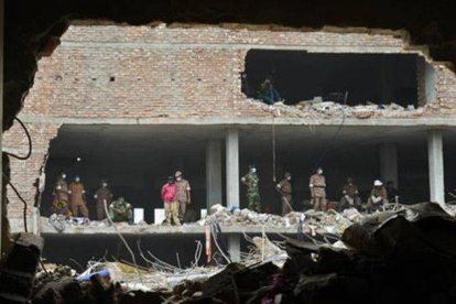 Miembros de los equipos de rescate observan los restos del edificio hundido en Savar, cerca de Dacca, este miércoles.