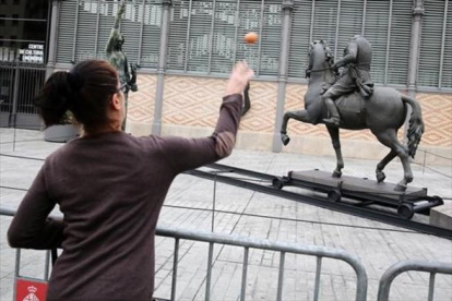 Una mujer prueba su puntería con la estatua de Franco.