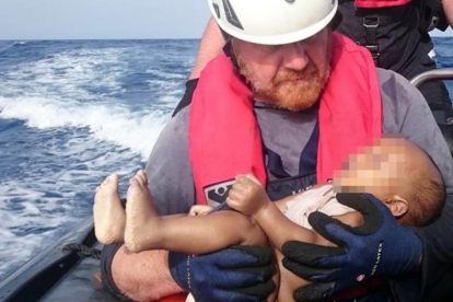 Un miembrod de la oenegé Sea Watch sostiene el cadáver de un bebé muerto recuperado de las aguas del Mediterráneo entre Libia e Italia.