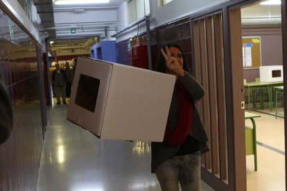 Una voluntaria hace el signo de la victoria antes de abrir el punto de participación, en Girona.