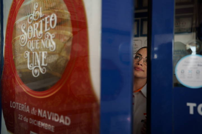 Una vendedora de lotería de la gasolinera La Chasnera, receptor de lotería en el municipio tinerfeño de Granadilla de Abona premiado en numerosas ocasiones, sigue por televisión el sorteo de la Lotería de Navidad que se celebra este jueves. RAMÓN DE LA ROCHA