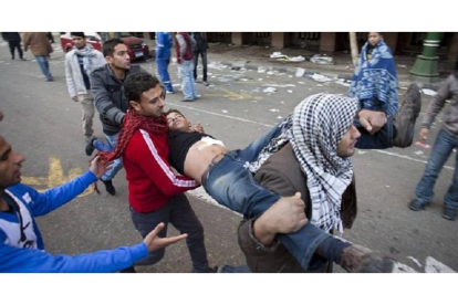 Unos manifestantes ayudan a un joven herido en los disturbios con la policía cerca de la plaza Tahrir, en El Cairo, hoy.