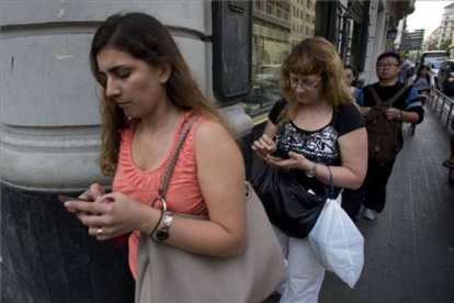 Usuarios de 'smartphones' chateando mientras caminan.