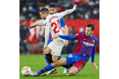 El sevillista Lucas Ocampos pelea por un balón con el jugador del Barcelona Nico González. VIDAL