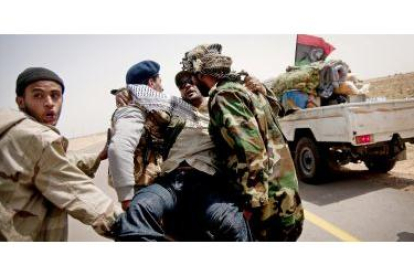 Rebeldes libios trasladan a un compañero herido entre Ras Lanuf y Ajdabiya.