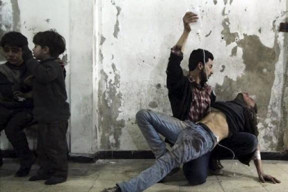 Un hombre da asistencia médica a un herido tras un ataque de las fuerzas del régimen al barrio de Duma, en Damasco.