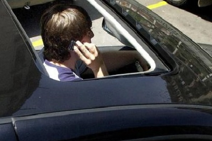 Un joven habla por teléfono mientras conduce.