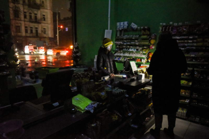 Vendedores usan sus teléfonos para tener luz en la tienda mientras se cortaba la electricidad en Kyiv. OLEG PETRASYUK