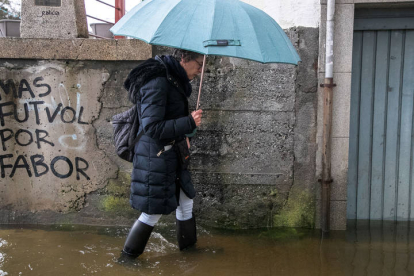 Una mujer camina por una zona inundada del barrio del Puente Romano en Lugo. ELISEO TRIGO