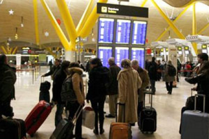 Varios viajeros miran los paneles de información de sus vuelos.