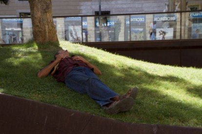 Un joven hace la siesta en una plaza, en una imagen de archivo.