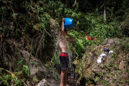 Un joven migrante se ducha en los montes de Ceuta, donde vive escapando de la deportación. BRAIS LORENZO