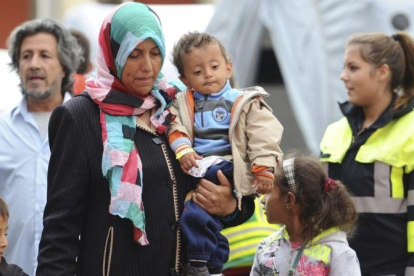 Una mujer y un niño, junto con otros migrantes y refugiados, son trasladados a un tren con destino a otra ciudad alemana poco después de su llegada a Múnich.