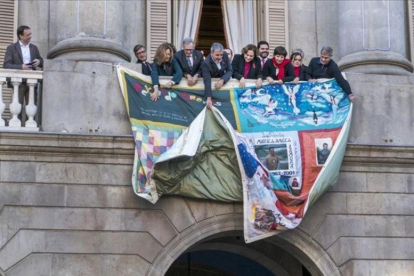Colocación del tapiz en la fachada del Ayuntamiento de Barcelona, donde se recuerda a los fallecidos por el sida en el último año.