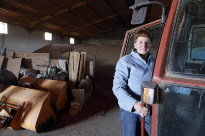 Una mujer agricultora, junto a su tractor.