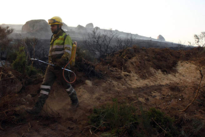Un miembro de una cuadrilla contra incendios, caminando sobre tierra quemada en el fuego de Porcarizas, el 17 de octubre.