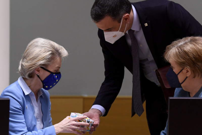 Sánchez le da un regalo a Ursula von der Leyen en presencia de Angela Merkel ayer, en Bruselas. JOHN THYS