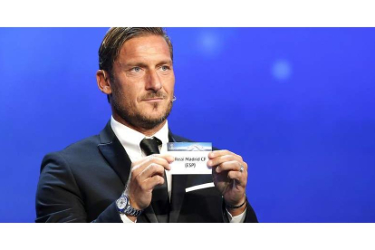 El exfutolista de la Roma Francesco Totti muestra la papeleta del Real Madrid durante el sorteo de la Liga de Campeones. SEBASTIEN NOGIER