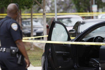 Un policía observa uno de los coches a los que disparó el autor del tiroteo de Santa Mónica.