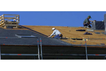 Colocadores de pizarra en un tejado de un edificio en construcción, en una imagen de archivo. L. DE LA MATA