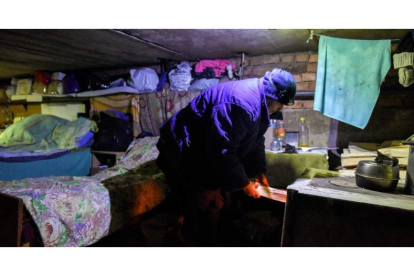 Una mujer pone leña en la estufa para calentar el sótano donde vive con sus vecinos en Siversk. OLEG PETRASYUK