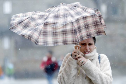 Una mujre se protege de la lluvia y el viento con un paraguas. LAVANDEIRA JR