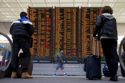 Dos viajeros comprueban la información de los vuelos en las pantallas del aeropuerto Charles de Gaulle, en Roissy (Francia).