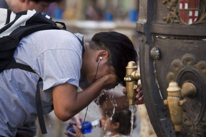 Un turista se refresca en la fuente de Canaletes durante una ola de calor.