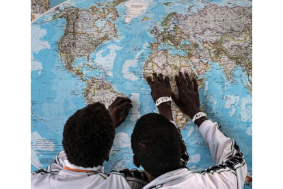 Dos personas inmigrantes localizan en el mapa su lugar de procedencia. EFE