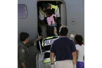 Un policía español ayuda a subir al avión a la única niña del grupo