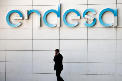 n hombre camina bajo el logo de Endesa en la sede de la empresa en Madrid