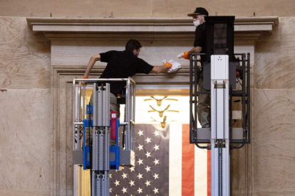 Dos trabajadores limpian ayer el interior del Capitolio tras el asalto. MICHAEL REYNOLDS