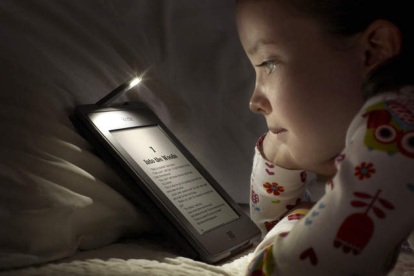 Imagen de archivo de una niña leyendo un libro en formato digital. FFE