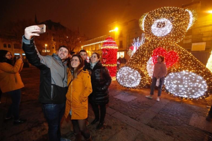 Un grupo de amigos se hace un selfie con el oso de luces en la plaza de San Marcelo.