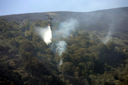 Uno de los helicópteros de extinción, actuando sobre el fuego, en Cármenes.