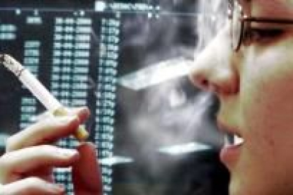 Una joven fuma un cigarrillo mientras trabaja frente a un ordenador