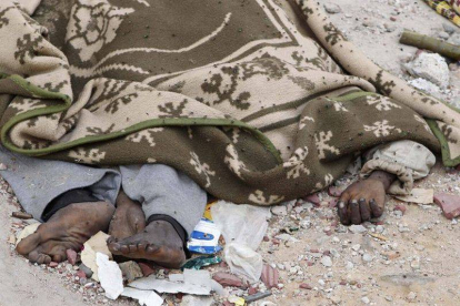 Un cadáver en descomposición, cubierto por una manta, en una calle de Sirte, el domingo.
