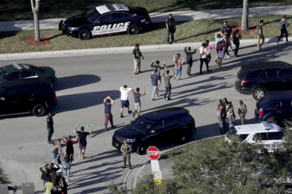 Evacuación de estudiantes con los brazos en alto a la salida del instituto Marjory Stoneman Douglas, en Parkland (Florida), el 14 de febrero.