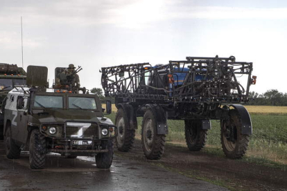 Militares rusos y sus vehículos pasan ante un tractor agrícola frente a un campo de trigo cerca de Melitopol. SERGEI ILNITSKY
