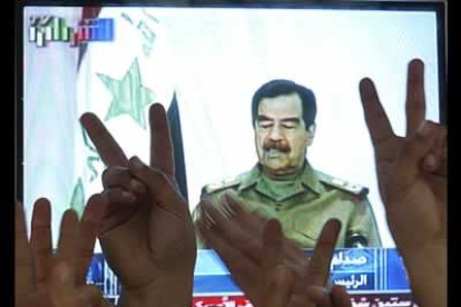 Un grupo de jordanos alzan los dedos en señal de victoria durante la comparecencia televisada de Sadam Huseín para demostrar que está vivo.