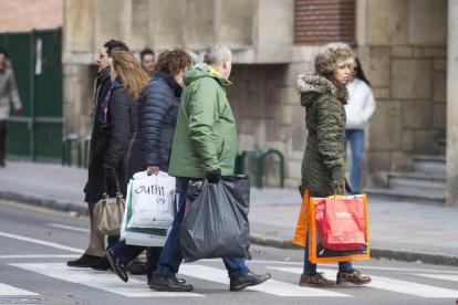 Varias personas llevan bolsas con compra durante una jornada de rebajas