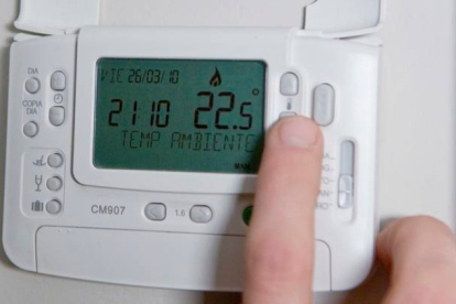Una persona bajando la temperatura del termostato. DL