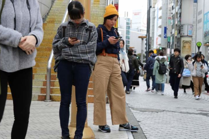 Jóvenes utilizan el móvil en las calles del barrio de Shibuya, en Tokio, que inspira a las marcas españolas.