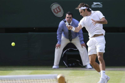 El tenista suizo Roger Federer devuelve una bola al canadiense Milos Raonic durante su encuentro de semifinales del torneo de tenis de Wimbledon, disputado en el All England Club en Londres (Reino Unido) hoy, viernes 4 de julio del 2014.