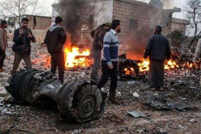 Un grupo de sirios deambula entre los restos del avión ruso derribado.