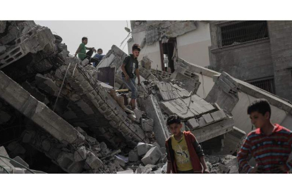 Un grupo de jóvenes palestinos camina sobre los restos de una casa bombardeada. MOHAMMED SABER