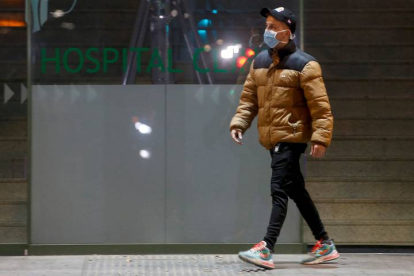 Un joven con mascarilla a su paso por el Hospital Clínic de Barcelona. QUIQUE GARCÍA